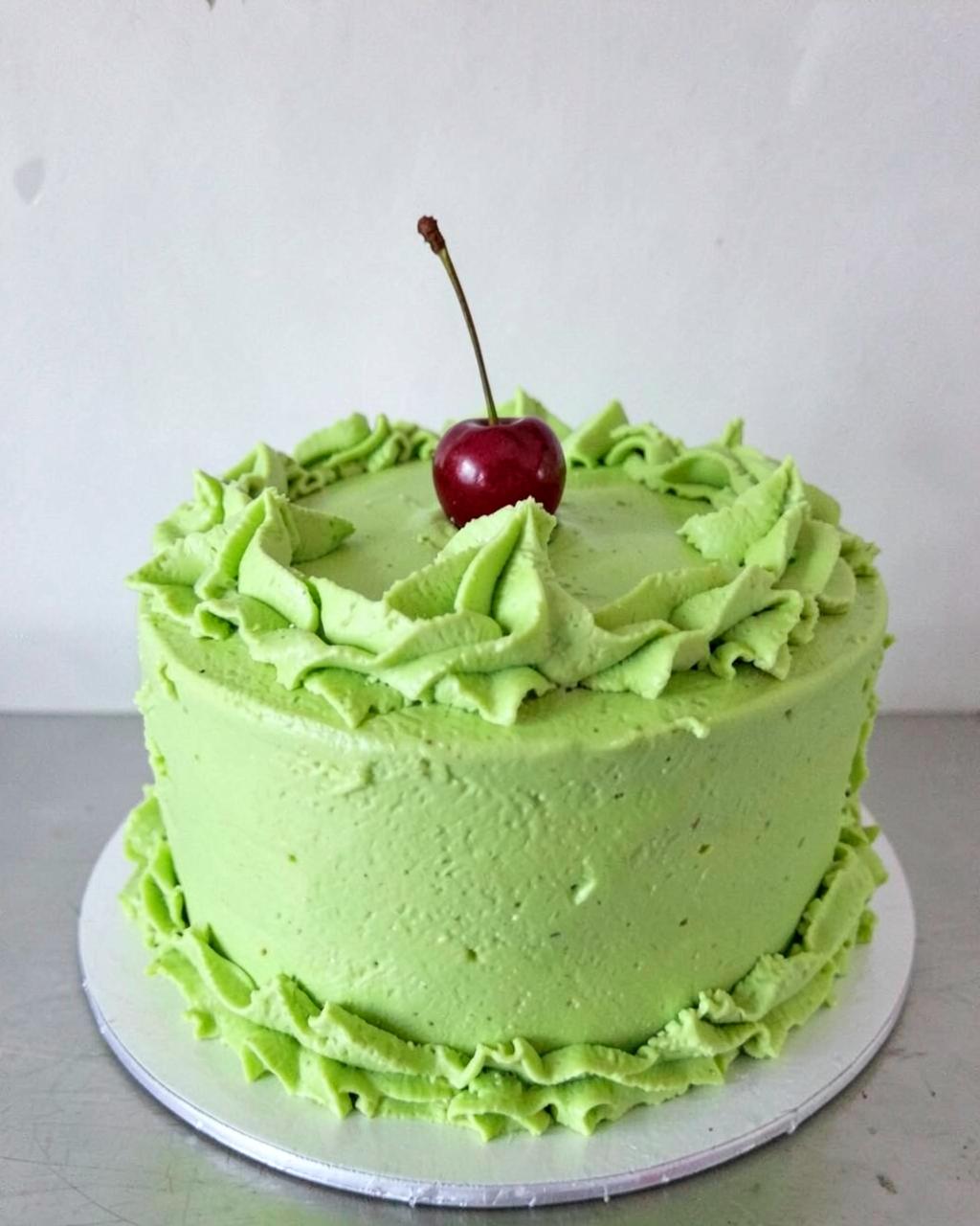 Lime green ruffled cake with a cherry